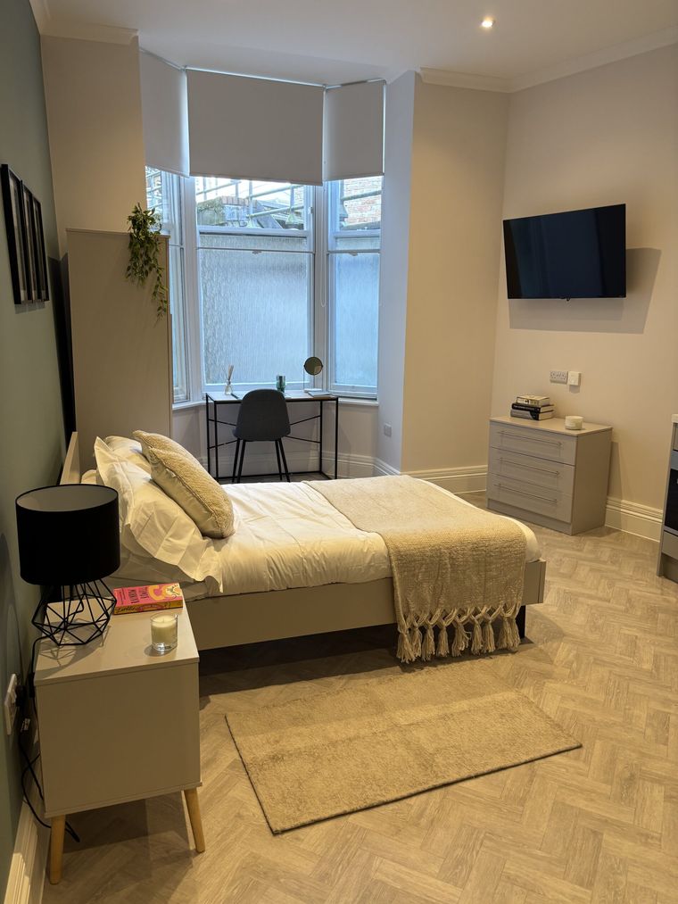 A Bright's House studio with a bay window, wall-mounted television and chest of drawers
